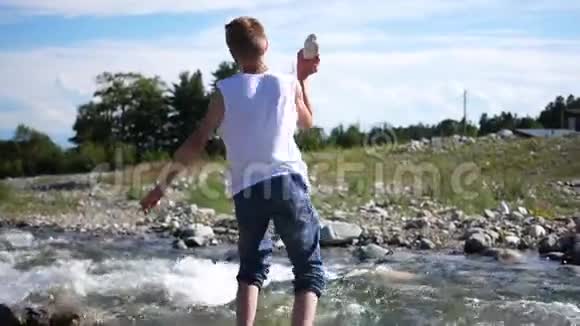 那家伙在河岸上玩把石头扔进水里冰冷的山河户外娱乐活动视频的预览图