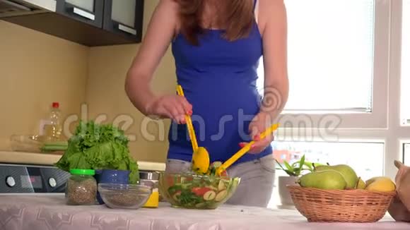 快乐孕妇将生态天然蔬菜沙拉拌在玻璃碗里视频的预览图