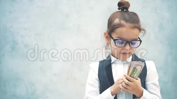 这位小商人站在灰色的背景上手里拿着美元在此期间一个教派视频的预览图