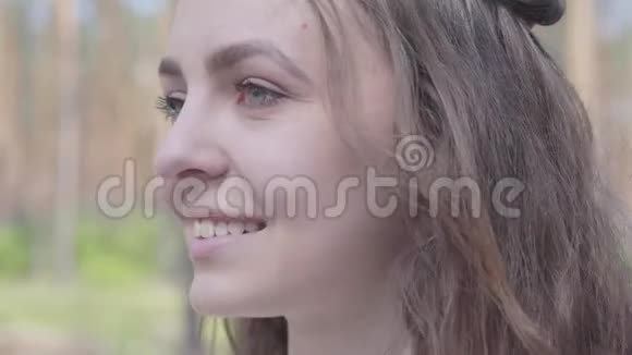 特写肖像幸福微笑的年轻女子环顾四周相机站在松林中野营的概念视频的预览图
