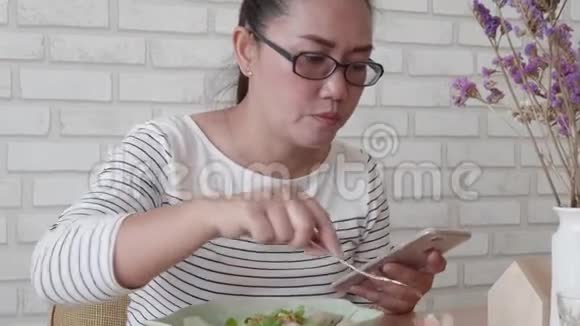 女士使用一个应用程序发送短信在她的智能手机设备同时吃沙拉视频的预览图