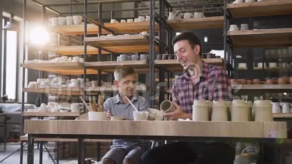 可爱的中年男人和他的小儿子在陶器里玩视频的预览图