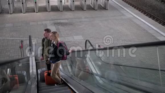 两名乘客站在火车站的移动楼梯上顶景视频的预览图