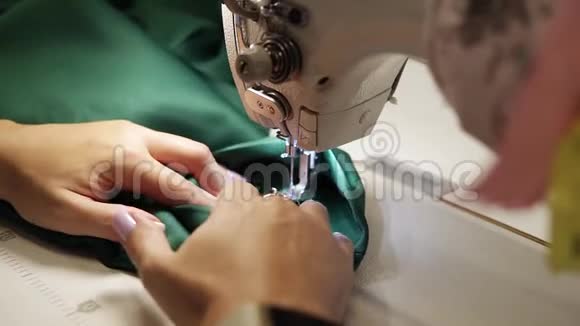 一个年轻女子的手用缝纫机缝制绿色织物女人手缝缝纫视频的预览图