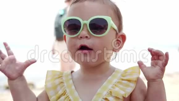 度假村海滩上戴太阳镜的小女孩有趣的小孩带着孩子旅行夏季海滨视频的预览图