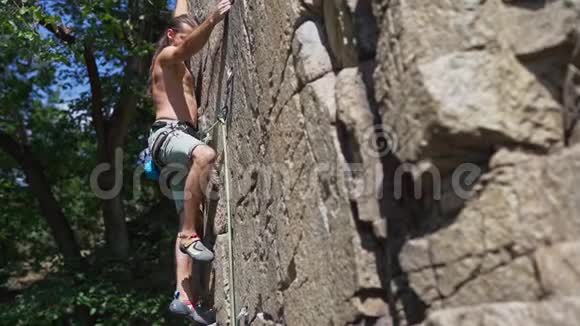 年轻的肌肉男攀岩者在艰难的运动路线上攀爬寻找到达和抓住视频的预览图