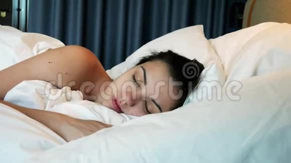 美丽的年轻女子在清晨醒来伸展身体躺在床上视频的预览图