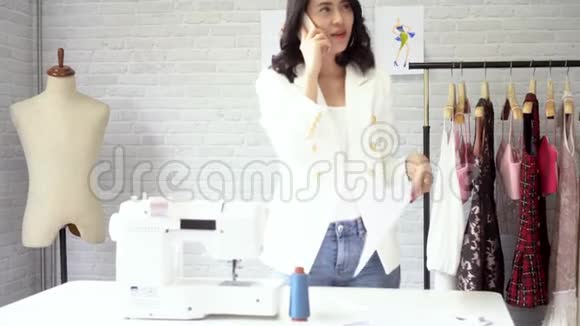 乐观的亚洲女企业家在工作室打电话给智能手机视频的预览图