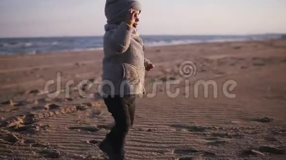 快乐的小幼儿跑到妈妈身边拥抱在秋天的沙滩上可爱的孩子抱着他妈妈他们摔倒了视频的预览图