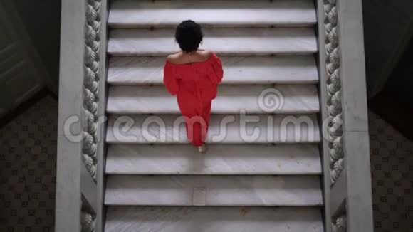 穿着高跟鞋的红衣女郎爬上一个大楼梯看着镜头视频的预览图