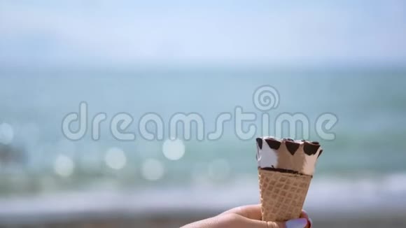在明亮的海洋背景下特写女性手拿着清爽的冰淇淋飞檐视频的预览图