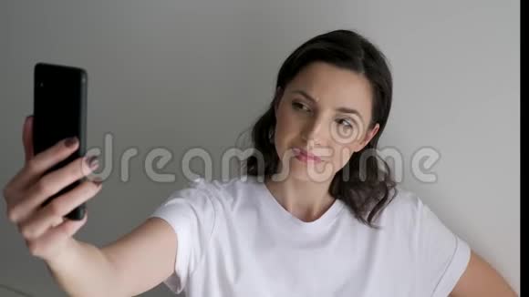穿着白色t恤的女人在光墙上自拍视频的预览图