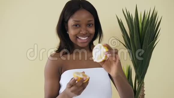 年轻的美国黑人妇女手中拿着柠檬半身在水疗中心的灯光背景健康的生活方式健康视频的预览图