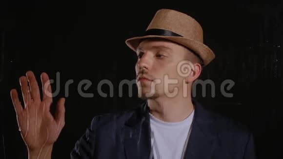 戴帽子和夹克的人碰玻璃视频的预览图