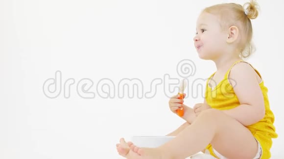 微笑的金发女婴在白色背景下吃她的饭视频的预览图