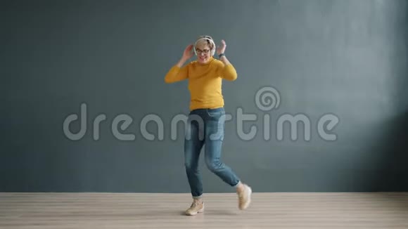 戴耳机跳舞的无忧无虑的女士独自享受歌声视频的预览图