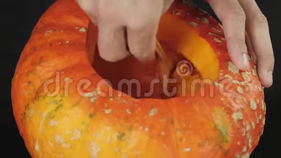 准备在万圣节制作灯笼用手在木桌上从一个橙色南瓜中舀取百事可乐种子视频的预览图