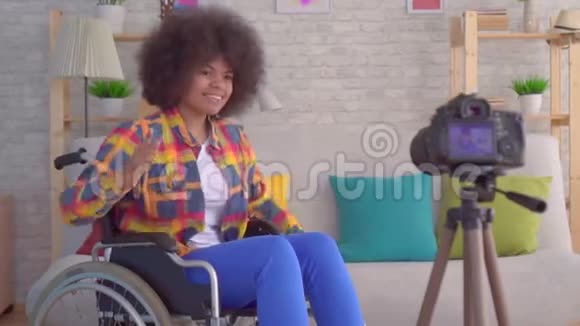 非洲女性博客写手残疾人坐在轮椅上留着非洲发型在镜头前录制视频视频的预览图