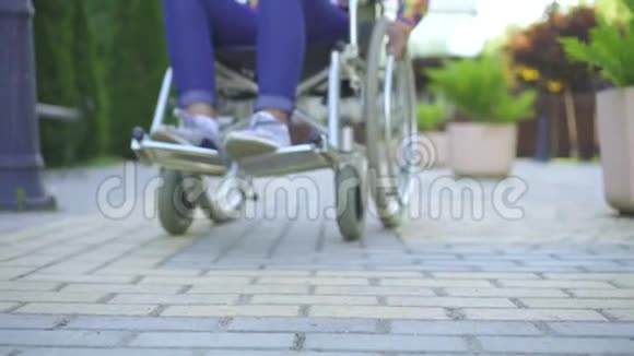 非洲女性发型是非洲的残疾的坐在轮椅上看着摄像机对着城市微笑视频的预览图