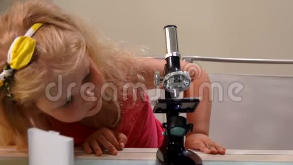 小女孩通过显微镜看起来很有趣视频的预览图