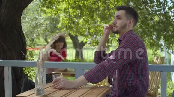 年轻的大胡子男人在前台喝茶而迷人的女孩则穿着复古的衣服在视频的预览图