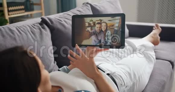 年轻的女士在网上和朋友聊天在家里用平板电脑打视频电话视频的预览图