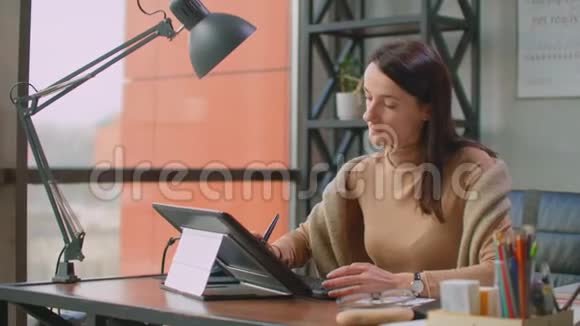 办公室里的一位专业设计师在办公室里坐着一个巨大的窗户在平板电脑上用手写笔画画视频的预览图