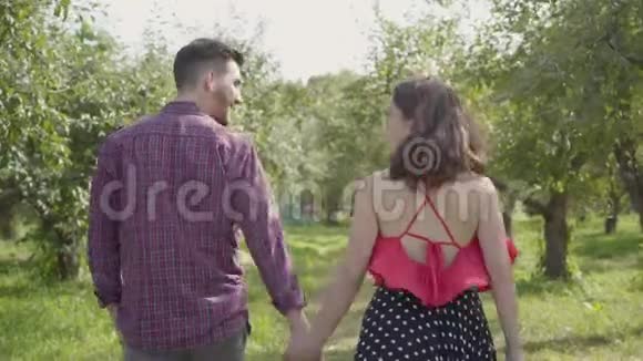 年轻积极的一对夫妇在花园里牵手交谈快乐的男人和女人视频的预览图