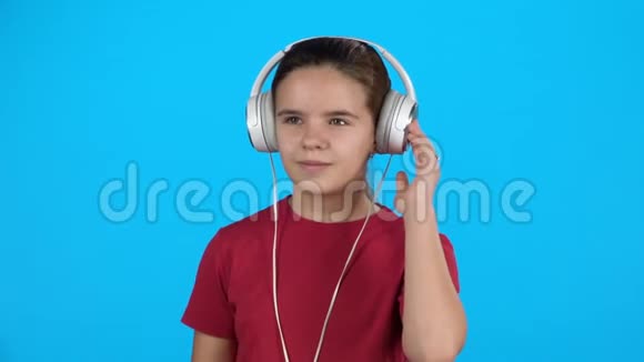 漂亮的孩子用耳机听音乐慢动作视频的预览图