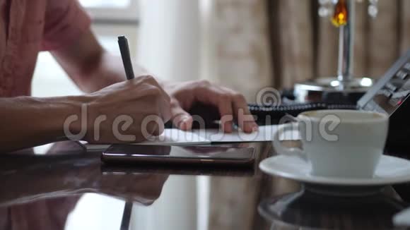 男作家坐在办公桌前喝咖啡一个人在纸上写字打字机就在他面前关门视频的预览图