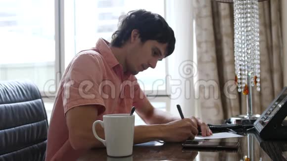男作家坐在办公桌前喝咖啡一个人在纸上写字打字机在他面前视频的预览图