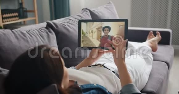 学生与男朋友在线交谈用平板电脑在沙发上打视频电话视频的预览图