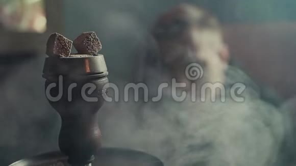 在厚厚的烟雾中在缓慢的运动中从碗中的钩子上取出燃烧的煤视频的预览图