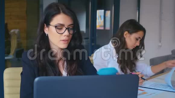 有魅力的年轻女商人在现代办公室的笔记本电脑上工作喝外卖咖啡视频的预览图