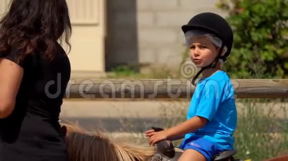 小男孩骑着小马挥动他的手视频的预览图