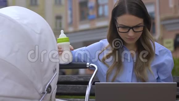 年轻的女商人在工作时试图喂养婴儿多任务视频的预览图