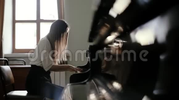 女钢琴家在窗户附近的大钢琴上缓慢地演奏古典音乐视频的预览图