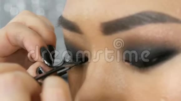 专业化妆师将假睫毛贴在美容院的一位亚洲韩国妇女的眼睛上视频的预览图