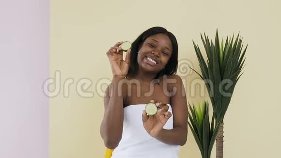 有趣的肖像拍摄美丽的非洲美国女人光滑的皮肤拿着一片黄瓜恢复皮肤的活力视频的预览图