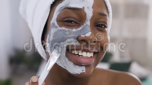 微笑的美国黑人女孩的特写镜头头上用毛巾敷面膜化妆视频的预览图