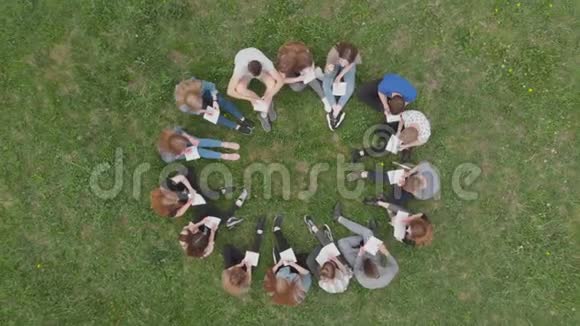 一群学生坐在一个圆圈里在草地上看书视频的预览图