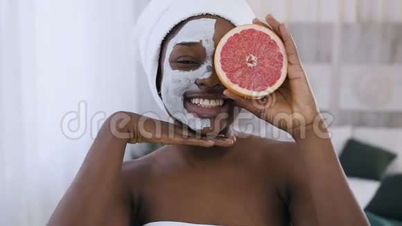 一张英俊的美国黑人年轻女子的肖像脸上戴着粘土面具手里拿着一半的葡萄柚视频的预览图
