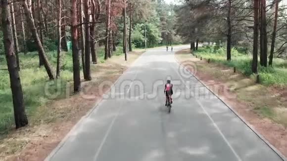 年轻漂亮的女孩骑自行车穿着粉红色的衣服在公园里骑自行车自行车的概念背面无人驾驶飞机视图视频的预览图