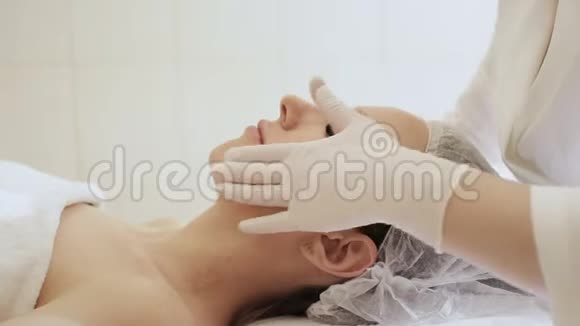 为年轻女性做面部按摩的白手套医生美容师视频的预览图
