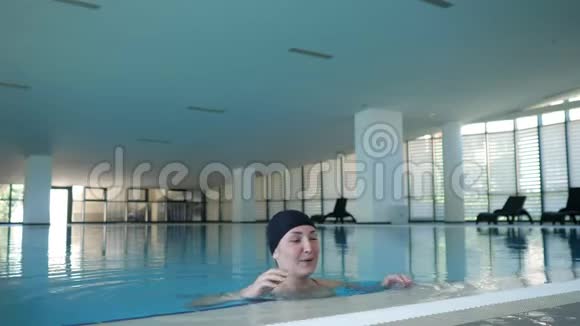 戴帽子的快乐女人爬出游泳池看着镜头视频的预览图