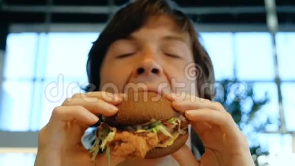 黑眼睛的家伙在模糊的窗户上吃美味的汉堡包视频的预览图