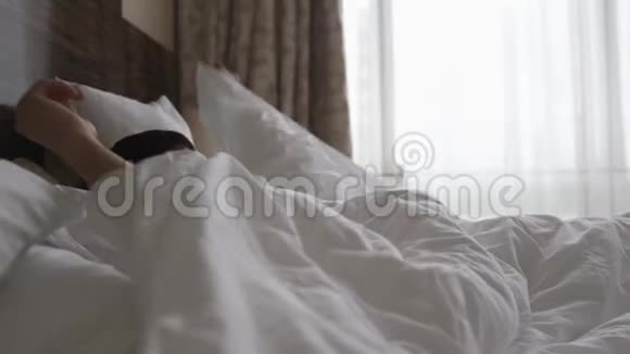 男人在床上醒来伸展身体揭开窗帘视频的预览图