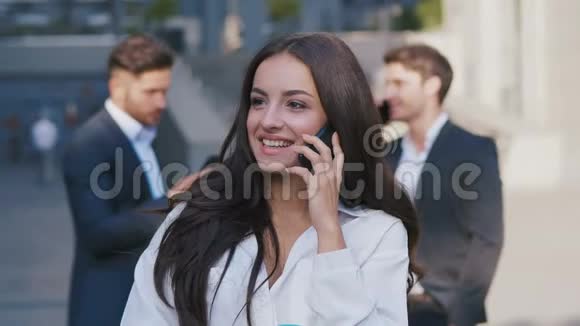 肖像美丽的年轻女商人在办公楼附近打电话女孩开朗快乐视频的预览图