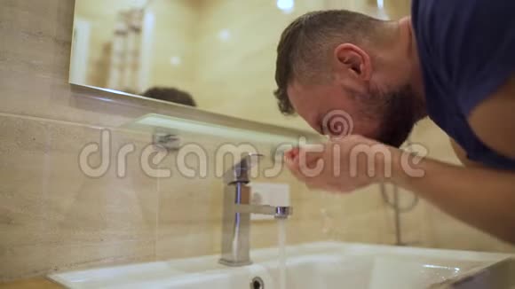早上的卫生男人在浴室里用清水洗脸慢动作视频的预览图