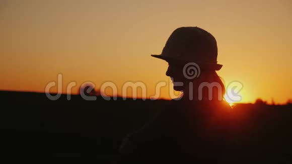 戴帽子的年轻女子欣赏风景如画的日落视频的预览图